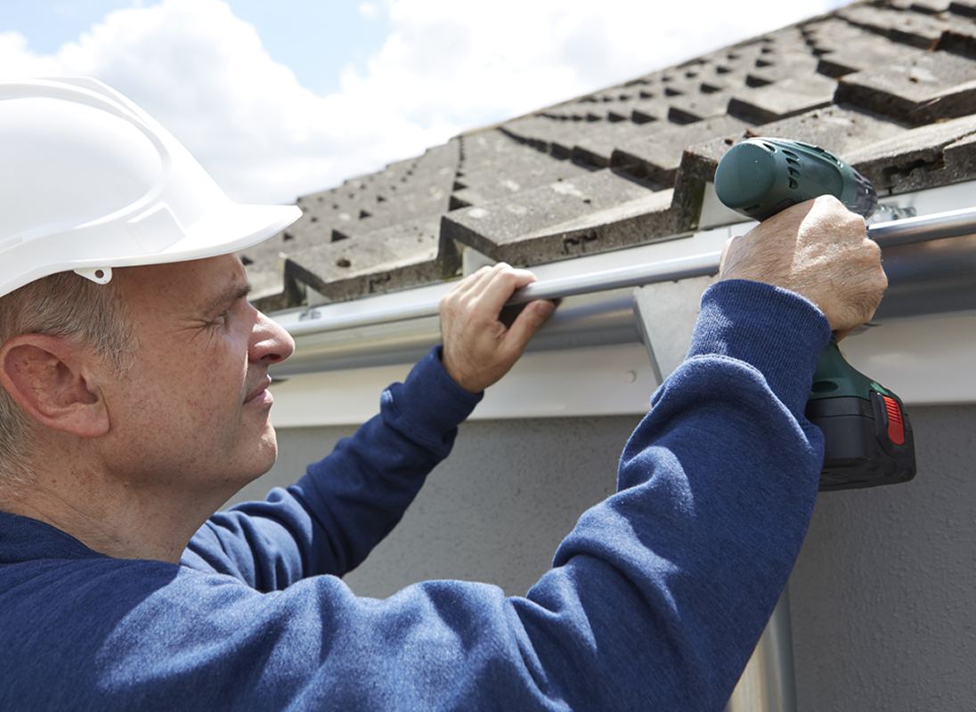 A contractor installing a seamless gutter along a home's roofline