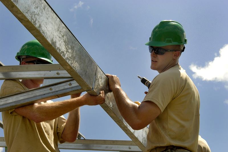 Two roofing contractors securing a truss on a job site